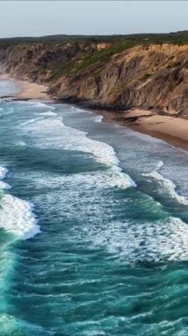 Güney Portekiz kıyı şeridinin büyüleyici güzelliğini tecrübe edin. Dalgaların kayalıklara çarpmasını ve kumlu kıyıların bozulmamış cazibesini göstermesini izleyin. Bu yolculuk zarafeti gösteriyor..