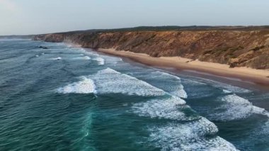 Portekiz 'in nefes kesici güney kıyı şeridini havadan bir perspektifle keşfedin. Dalgalar kayalık kayalıklara çarparken, kumlu kumsallar kıyı boyunca uzanıyor ve güzellikleri gözler önüne seriyor..