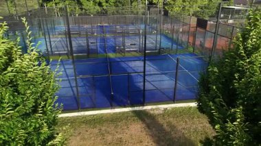 Eğlence tesisinde birden fazla tenis kortu görülebilir. Oyuncular parlak güneş ışığı altında, çevreleyen canlı bir ortamda çeşitli beceriler sergileyen maçlara katılıyorlar..