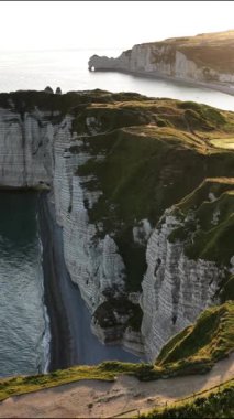 Güneş batarken, Normandiya 'daki Etretat' ın nefes kesen uçurumlarını keşfedin. Sahil şeridi boyunca uzanan eşsiz kaya oluşumlarını ve huzurlu suları aydınlatın..