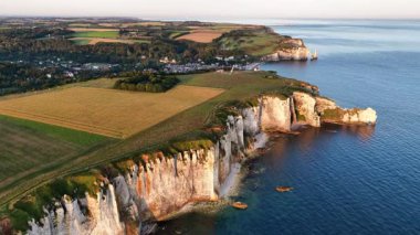 Gün batımında, Normandiya 'da Etretat' ın nefes kesen uçurumlarını canlı renklerle, ufuk çizgisini aydınlatan ve engebeli kıyı güzelliğini her anını büyüleyen.