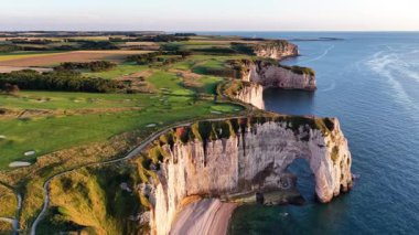 Fransa 'nın Etretat kentindeki muhteşem kıyı kayalıklarını keşfedin. Gün batımında yemyeşil manzaralar, engebeli kıyı şeritleri ve sakin suları aydınlatarak sakin bir atmosfer yaratın..