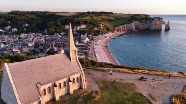 Fransa, Etretat 'ın çarpıcı güzelliğini yukarıdan görün. Hava perspektifi, ufukta güneş batarken dramatik uçurumları, kumlu sahili ve büyüleyici kasabayı vurgular..