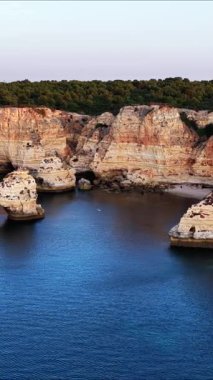 Portekiz, Algarve 'nin baş döndürücü uçurumlarını ve kristal berraklığında sularını keşfedin. Bu hava manzarası, altın saat boyunca kıyı şeridinin doğal güzelliğini gösteriyor..