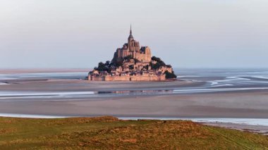 Gündoğumunda Normandie 'deki Abbaye du Mont-Saint-Michel' in çarpıcı hava manzarasını izleyin. Adaların eşsiz yapısı çevresindeki denizden görkemli bir şekilde yükseliyor ve zengin tarihini gözler önüne seriyor..