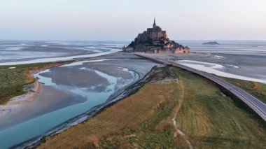 Abbaye du Mont-Saint-Michel 'in muhteşem güzelliğini yukarıdan görün. Tarihi mimarisini ve gün batımında etrafını çevreleyen gelgit manzaralarını gösterin..