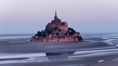 Abbaye du Mont-Saint-Michel 'in alacakaranlıkla yıkanmış nefes kesici görüntüsünü tecrübe edin. Gelgit adalarının eşsiz mimarisi Normandiya kıyı şeridinin sakin zemininde göze çarpar..