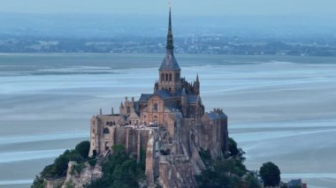 Abbaye du Mont-Saint-Michel 'in Normandie' nin üzerine alacakaranlık çöktüğünde nefes kesici hava manzarasını keşfedin, büyüleyici mimarisini ve etrafındaki suları vurgulayın. Huzurlu bir an yakalandı.