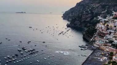 Canlı günbatımının Positano üzerindeki gökyüzünü nasıl değiştirdiğini izleyin. Sakin sularda dinlenen sahil köyünü ve teknelerini aydınlatıyor. İtalya 'nın dingin güzelliğini ve çekiciliğini tecrübe et..
