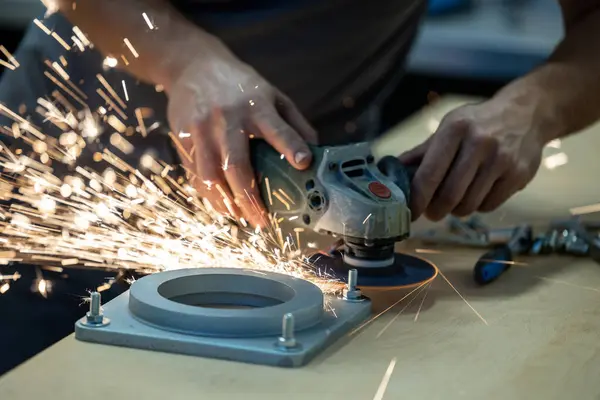 Man using a power tool to cut away a bolt, sparks are strongly visible