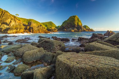 Okyanus Dalgaları Kayalara Karşı Çarpıyor Lush Green Hills ile Endonezya 'da Huzurlu Yeşil Tepeler Oluşturuyor