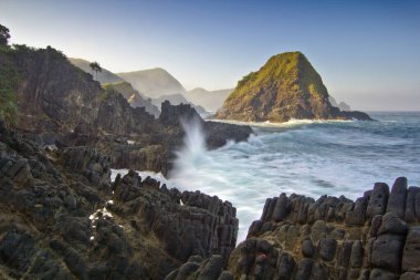 Güneş doğarken okyanus dalgaları Rocky Sahiline çarpıyor Volkanik Kaya oluşumlarıyla şaşırtıcı deniz manzarası yaratıyor Telawas Sahili Lombok Endonezya 'dan görkemli bir şekilde yükseliyor