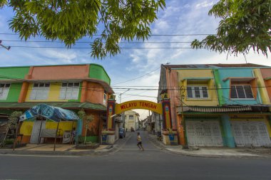 Colorful Buildings Line a Street with Traditional Archway in a Vibrant Neighborhood, Quietly with Charm at Ampenan Old City, Lombok Indonesia. clipart