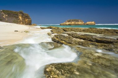 Tropikal Sahil Dalgaları Kayaların Üzerinden Akıyor, Ada ve Kayalıklar Sungkun Plajı Lombok Endonezya ile Sakin Kıyı Manzarası Oluşturuyor