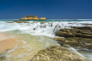 Okyanus Dalgaları Kayalara Çarpıyor Kumsalda yavaşça Şelale etkisi yaratıyor Uzak Ada Manzaralı Sungkun Plajı Lombok Endonezya