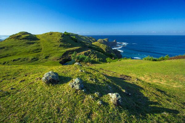 Green Hills Meet the Blue Ocean on a Sunny Day at the Coast with Lush Vegetation Tranquilly at Mereje Hills, Lombok, Indonesia