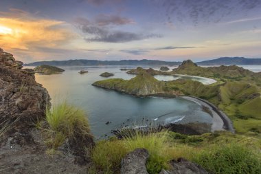 Ada Sahil Hattı, Scenic Sunrise 'da Lush Green Hills ve Sakin Okyanus Suyu ile buluşuyor. Padar Adası, Komodo Bölgesi, Labuan Bajo Endonezya.