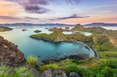 Ada peyzajı, Komodo Bölgesi, Labuan Bajo Endonezya 'da, Padar Adası' ndaki Sunset 'te Lush Green Hills ve Dramatik Gökyüzü ile Okyanus Manzaraları ve Manzaraları Gösteriyor.