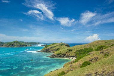 Tropikal Ada, Endonezya 'nın Lombok kentindeki Merese Tepesi' nde Lush Green Hills 'le Turkuaz Okyanus Suyu' nu kucaklıyor.