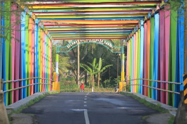 Colorful Bridge Spans Across Rural Landscape with Vibrant Colors and Tropical Plants clipart