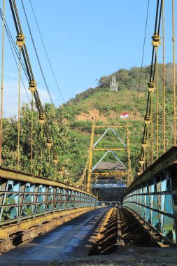 Askı Köprüsü Lush Vadisi 'ni Bayraklar ve Altyapı ile geçiyor Mavi Gökyüzü Altında Güzelce Gösteriliyor