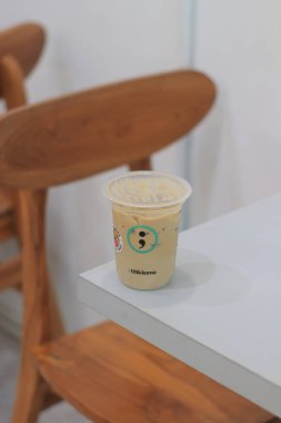 Buzlu kahve, ahşap mobilyaların yanındaki beyaz masaya oturur.