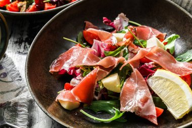 Prosciutto etli lezzetli salata, kızarmış ekmek, roka, domates, kırsal ahşap arka planda marul. Sağlıklı yiyecekler, kapatın.