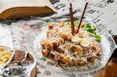 Cam kasede Sezar salatası, yumurta, peynir, kızarmış ekmek ve peçeteli ahşap kırsal arka planda tavuk. Sağlıklı yiyecekler, kapatın.