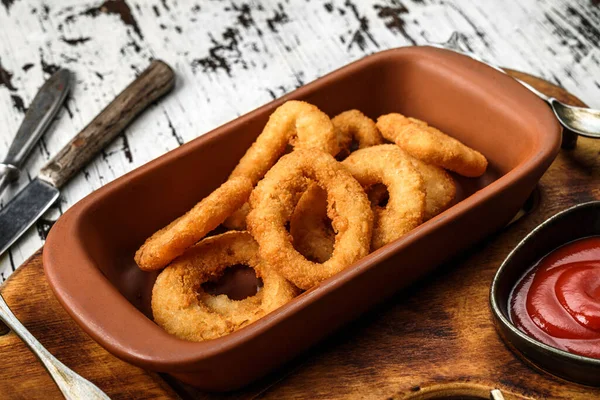Crunchy fried squid rings breaded with tomato sauce in wooden background, beer snacks. Fried calamari squid appetizer