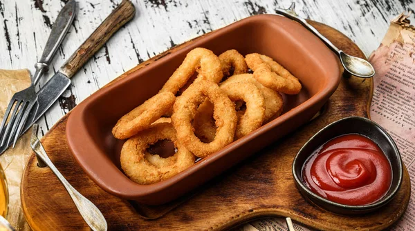Crunchy fried squid rings breaded with tomato sauce in wooden background, beer snacks. Fried calamari squid appetizer