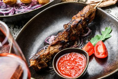 Sebzeli ve tabağında domates soslu ızgara et şişi. Sağlıklı yiyecekler. Sıcak et yemekleri, kebap yemekleri, yakın çekim, seçici odaklanma.