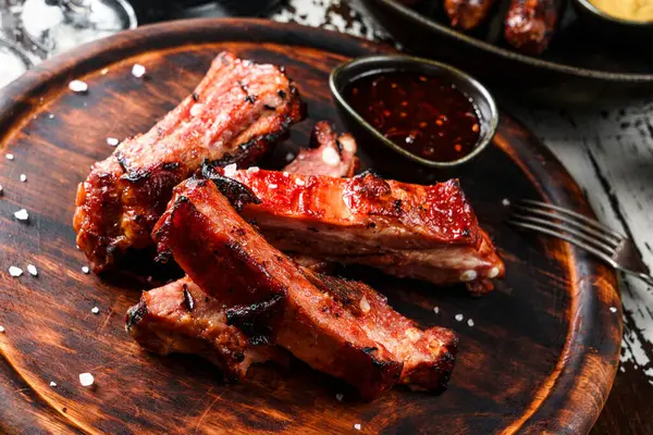 Barbecue pork spare ribs with hot honey chilli marinade on wooden cutting board with sauce on rustic background. Top view