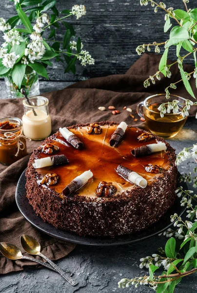 Karamelli çikolatalı pasta, yoğunlaştırılmış süt, krema ve fındıklı ve bahar çiçekli koyu fındıklı. Tatlılar, tatlı ve pasta, üst manzara