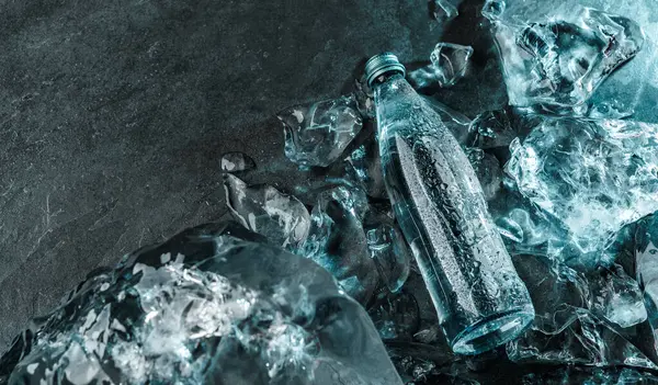 Бутылка Воды Льду Каменном Фоне Кусочки Льда Освещаются Синим Светом — стоковое фото