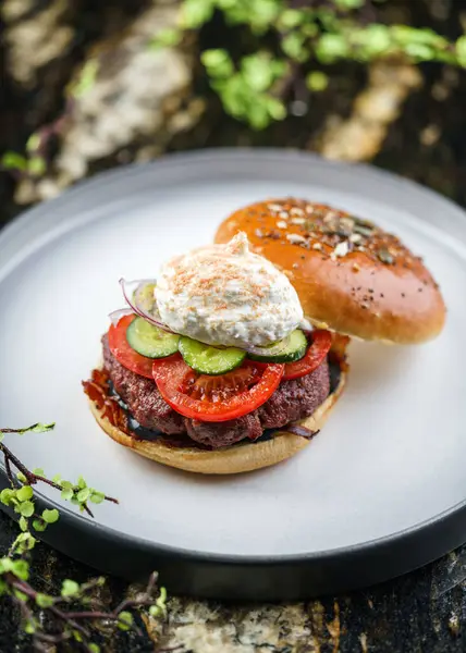 Beef burger with poached egg or Eggs Benedict, tomatoes, cucumbers, sauce and fried meat cutlet on marble background. Hamburger, breakfast, top view, close up