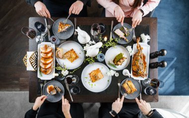 Aile evde tatil masası için yemek yiyor. Paskalya bayramı masasında pişmiş et filetosu, kaburga eti, kaburga kemiği, kuzu but, şarap kadehleri, turtalar, dekorasyon. Mutlu Paskalyalar, üst görünüm