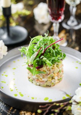 Salata Olivier, somon, yeşillik ve mermer kaplama, süslemeli, çiçekli ve şarap bardaklı. Tatil yemeği, üst manzara.