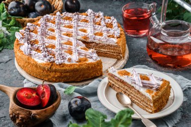 Gri arka planda kremalı ve erikli lezzetli bisküvi keki çay, çiçekler, dantel peçeteler. Tatlılar, tatlı ve pasta, ev yapımı kekler, üst görünüm, seçici odaklanma