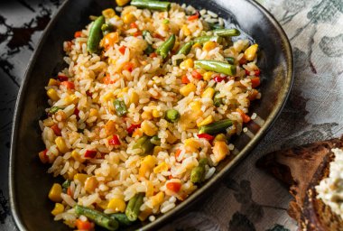 Sebzeli lezzetli pilav, fasulye, tahtadan yapılmış mısır tabağı. Vejetaryen yemeği, üst manzara, yakın çekim.