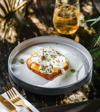 Çırpılmış yumurtalı lezzetli sandviç, parmesan peyniri, mantar sosu, mikro yeşiller ve meyve suyuyla servis edilen tohumlar. Sağlıklı kahvaltı, sabah ışığı, üst manzara.