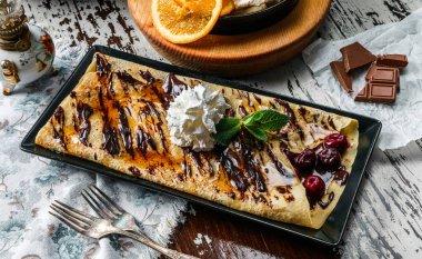 Kirazlı krep, çikolata ve kırsal arka planda krema. Tatlılar, tatlı ve pasta, üst manzara