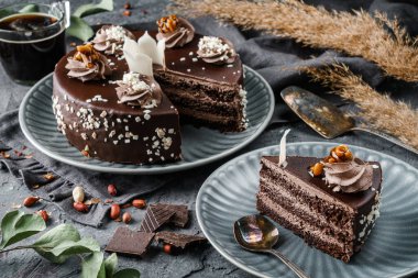 Koyu taşlı arka planda kremalı çikolatalı bisküvi, bitki ve fındıklı. Tatlılar, tatlı ve pasta, üst manzara, kapat.