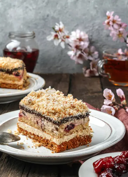 Bir parça kiraz ve kremalı bisküvi. Ahşap zemin üzerinde reçel ve çiçeklerle birlikte. Tatlılar, tatlı ve pasta, ev yapımı kekler, yakın plan, seçici odaklanma