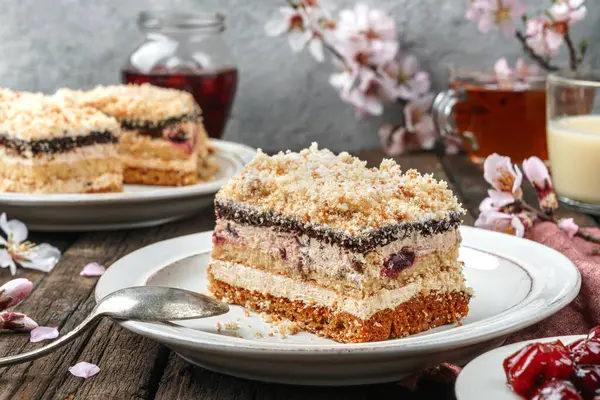 Bir parça kiraz ve kremalı bisküvi. Ahşap zemin üzerinde reçel ve çiçeklerle birlikte. Tatlılar, tatlı ve pasta, ev yapımı kekler, yakın plan, seçici odaklanma