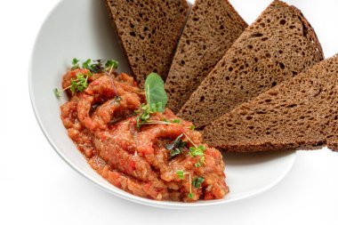 Sebzeli patlıcan salatası ve beyaz arka planda izole edilmiş tabakta bir dilim ekmek. Sağlıklı vejetaryen yemekleri, üst manzara, yakın çekim.