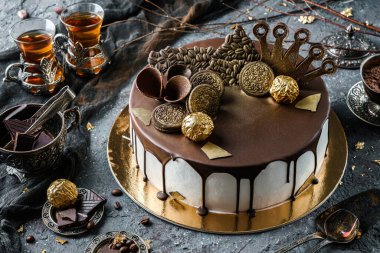 Çikolatalı Oreo bisküvisi, altın şekerli ve siyah taştan arkaplanlı kurabiye ve bir fincan çay. Tatil tatlısı, tatlı ve pasta, yakın çekim, üst manzara