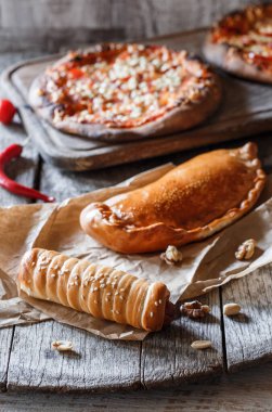 Ev yapımı fırın, hamurda sosis, cheburek etli turta ve ahşap zemin üzerinde pizza. Fast food, hamur işi ve fırın, seçici odak