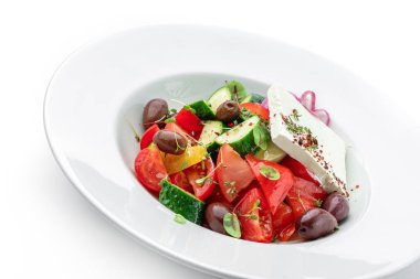 Domatesli, soğanlı, dolmalık biberli, salatalıklı, zeytinli, beyaz arkaplanlı taze sebzeli Yunan salatası. Sağlıklı yiyecekler, vejetaryen diyeti, üst manzara, yakın çekim.