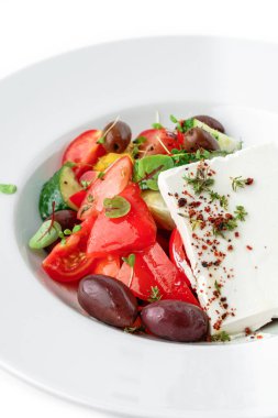 Domatesli, soğanlı, dolmalık biberli, salatalıklı, zeytinli, beyaz arkaplanlı taze sebzeli Yunan salatası. Sağlıklı yiyecekler, vejetaryen diyeti, üst manzara, yakın çekim.