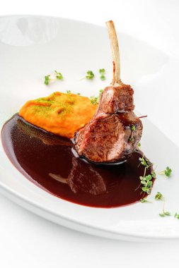 Kızarmış kuzu pirzolası ya da pirzola eti, sebze püresi ve beyaz arka planda izole edilmiş tabakta sos. Et tabakları, üst manzara, kapatın.